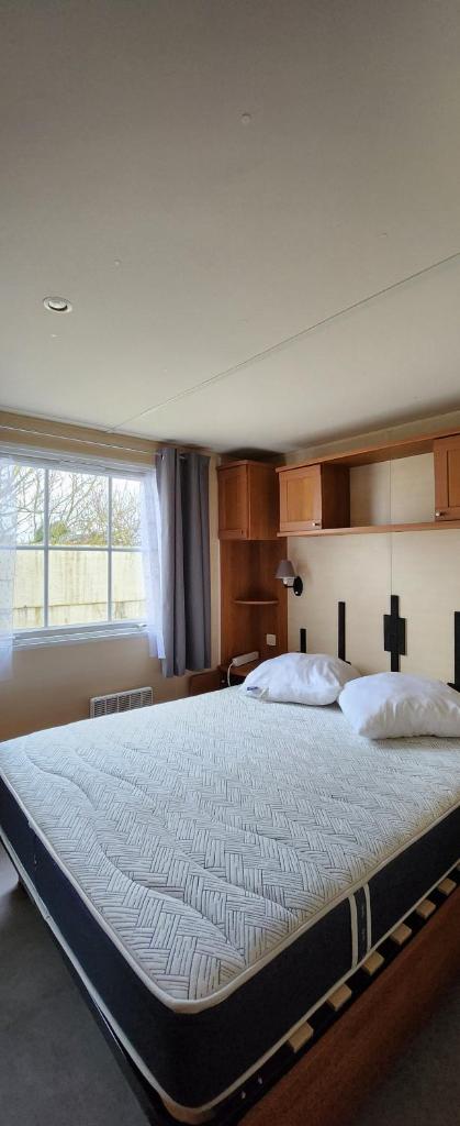 un grand lit dans une chambre avec une grande fenêtre dans l'établissement Camping Le clos Savoye, à Biville-sur-Mer