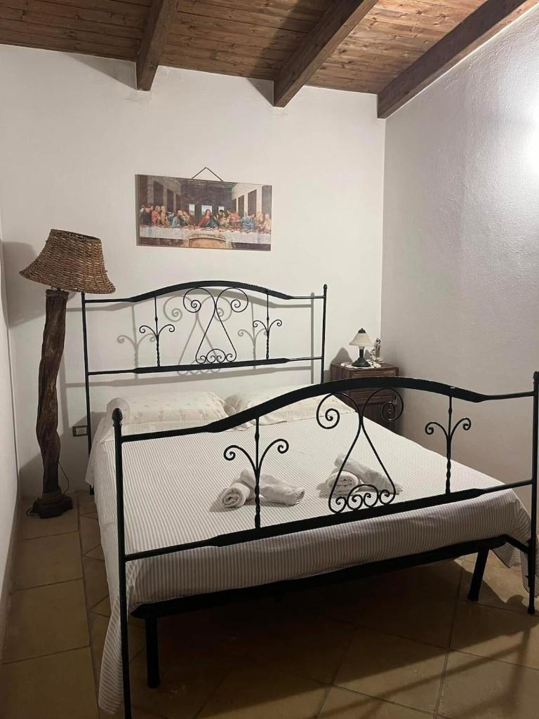 - une chambre avec un lit en fer forgé et une lampe dans l'établissement Villa Rosa, à Alessano