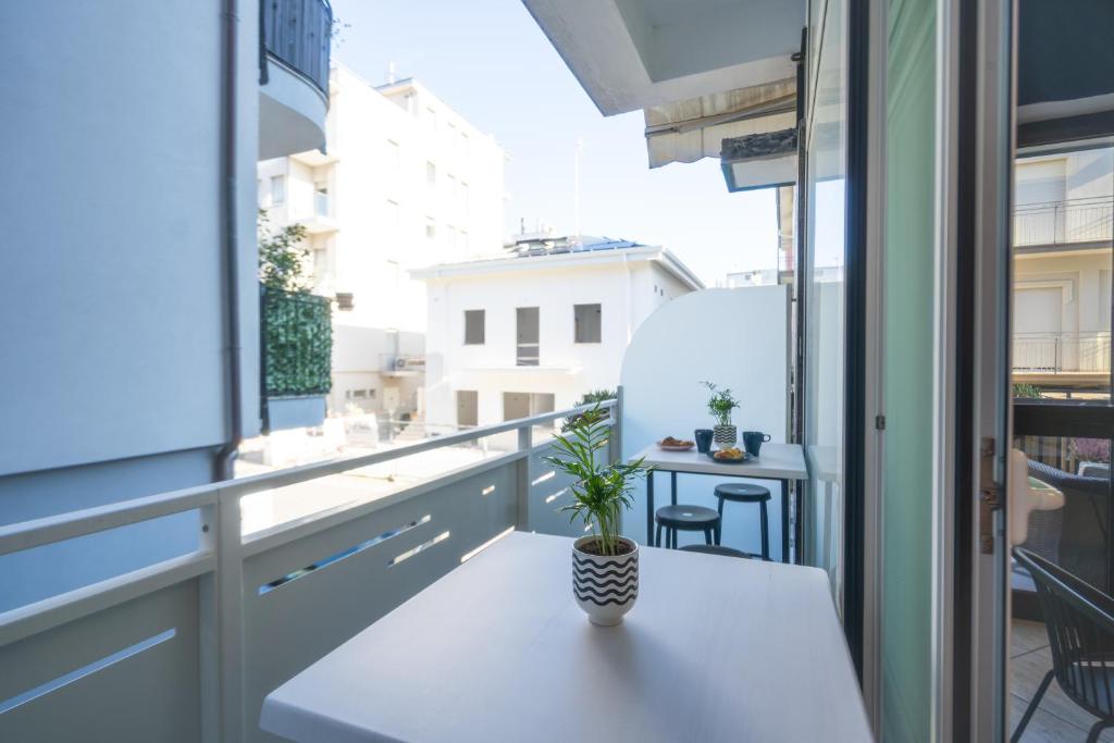 d'un balcon avec une table et une plante en pot. dans l'établissement Hotel Aldebaran, à Rimini