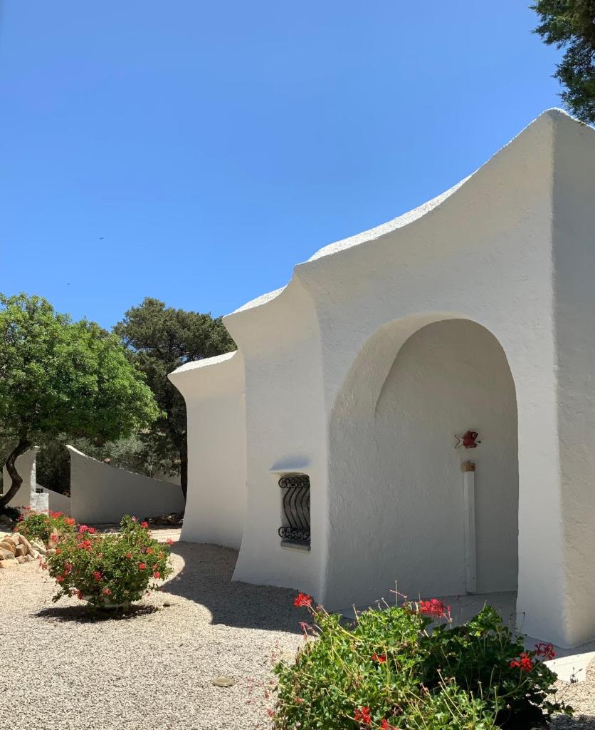 - un bâtiment blanc avec une cour fleurie dans l'établissement Sa Maluni, à Marongiu