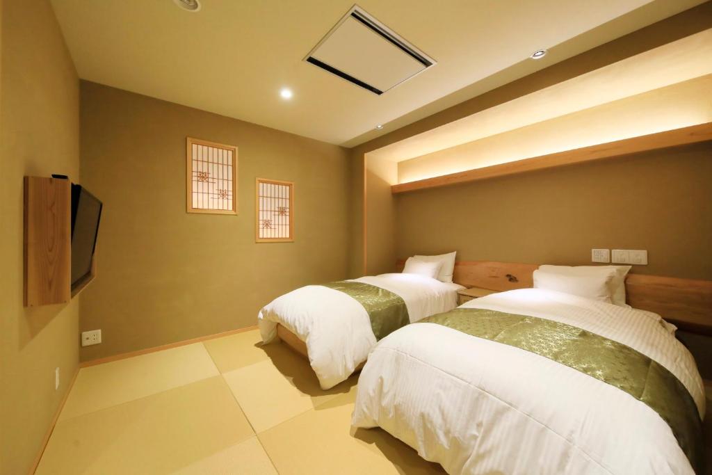 une chambre avec deux lits et une télévision à écran plat dans l'établissement Ryokan Biyunoyado, à Yamanouchi