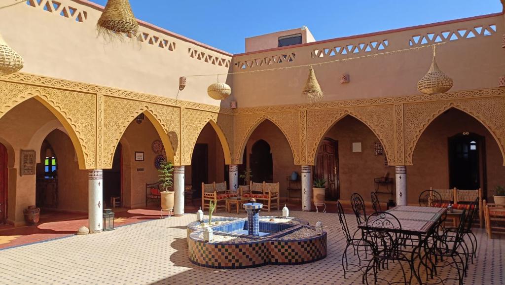 une cour avec une fontaine, des tables et des chaises dans l'établissement Riad Dar Poublanc, à Merzouga