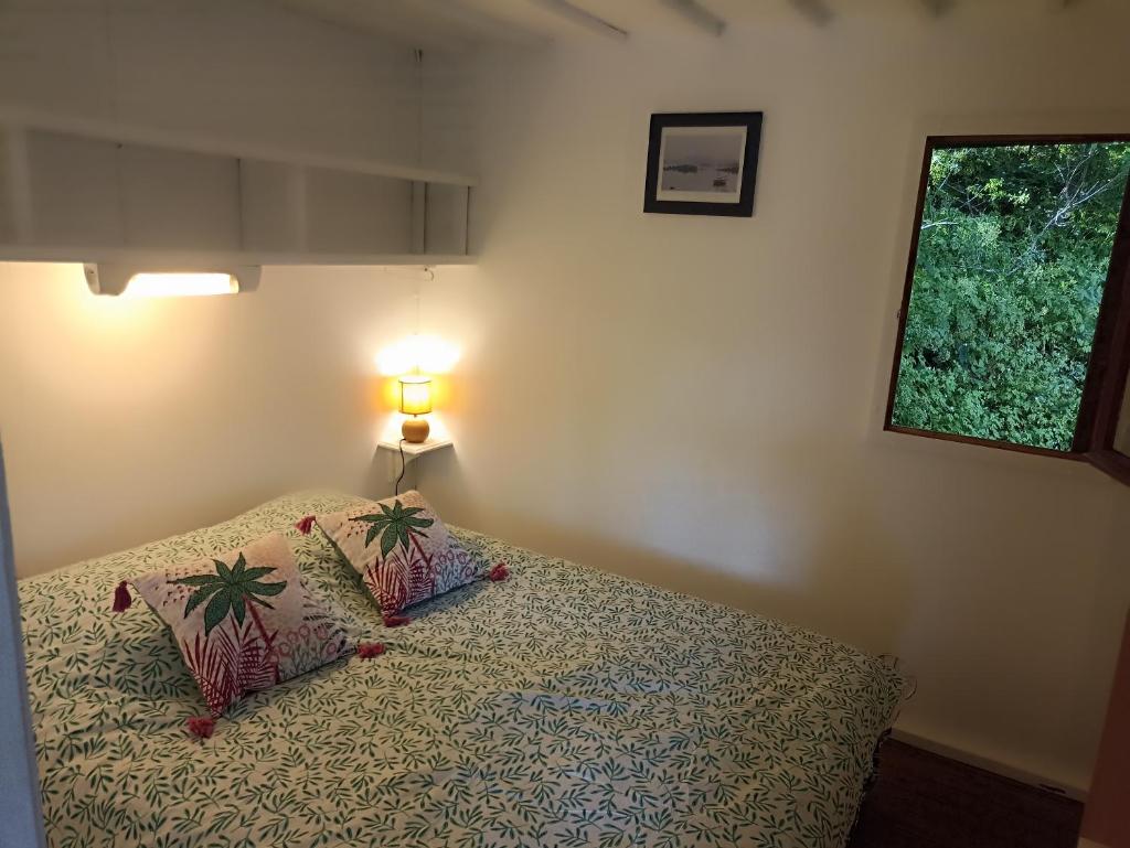 une chambre avec un lit avec une lampe et une fenêtre dans l'établissement Les cabanes de l'île aux oiseaux Guern, à Guern