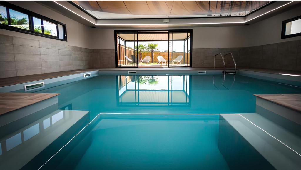 une piscine avec de l'eau bleue dans une maison dans l'établissement LE REFUGE DU LAC - Séjour d'Exception avec Vue imprenable sur le Lac - Piscines Sauna Salle Fitness Bibliothèque Restaurant - 10min des Sables d'Olonne, à Sainte-Foy