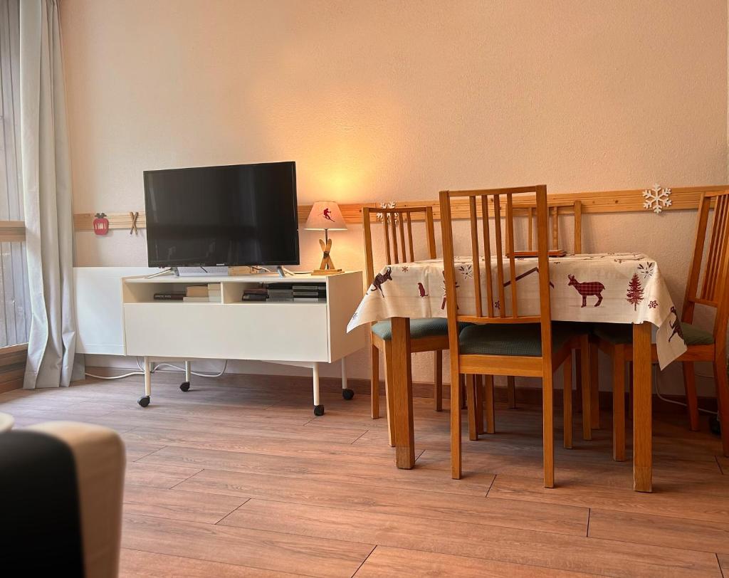 un salon avec une télévision et une table avec des chaises dans l'établissement Carla's Residences - Le Margériaz, à Aillon-le-Jeune