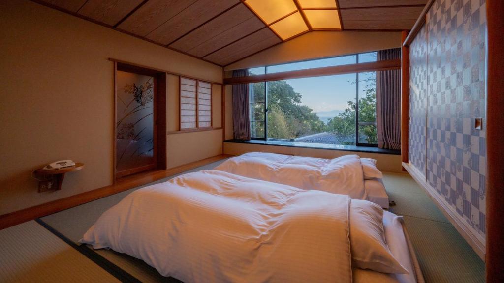 une chambre avec deux lits et une grande fenêtre dans l'établissement Nishiizu Koyoi, à Numazu 37 autres photos