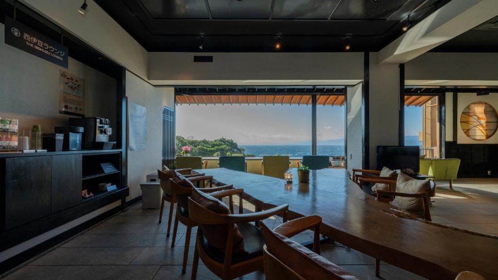 un restaurant avec une table, des chaises et une grande fenêtre dans l'établissement Nishiizu Koyoi, à Numazu
