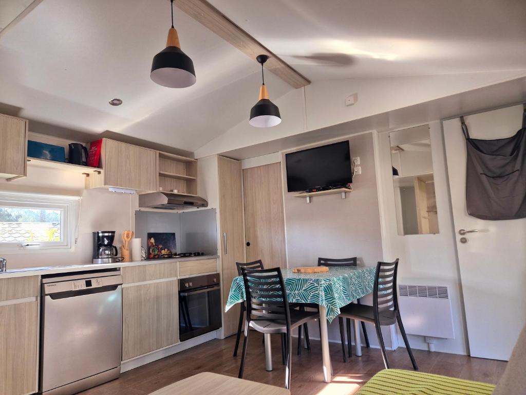 une cuisine et une salle à manger avec une table et des chaises dans l'établissement MH 467 Isalisa 3chambres et 1 salle de bain dans camping 4 étoiles avec PARC AQUATIQUE, à Saint-Julien-en-Born