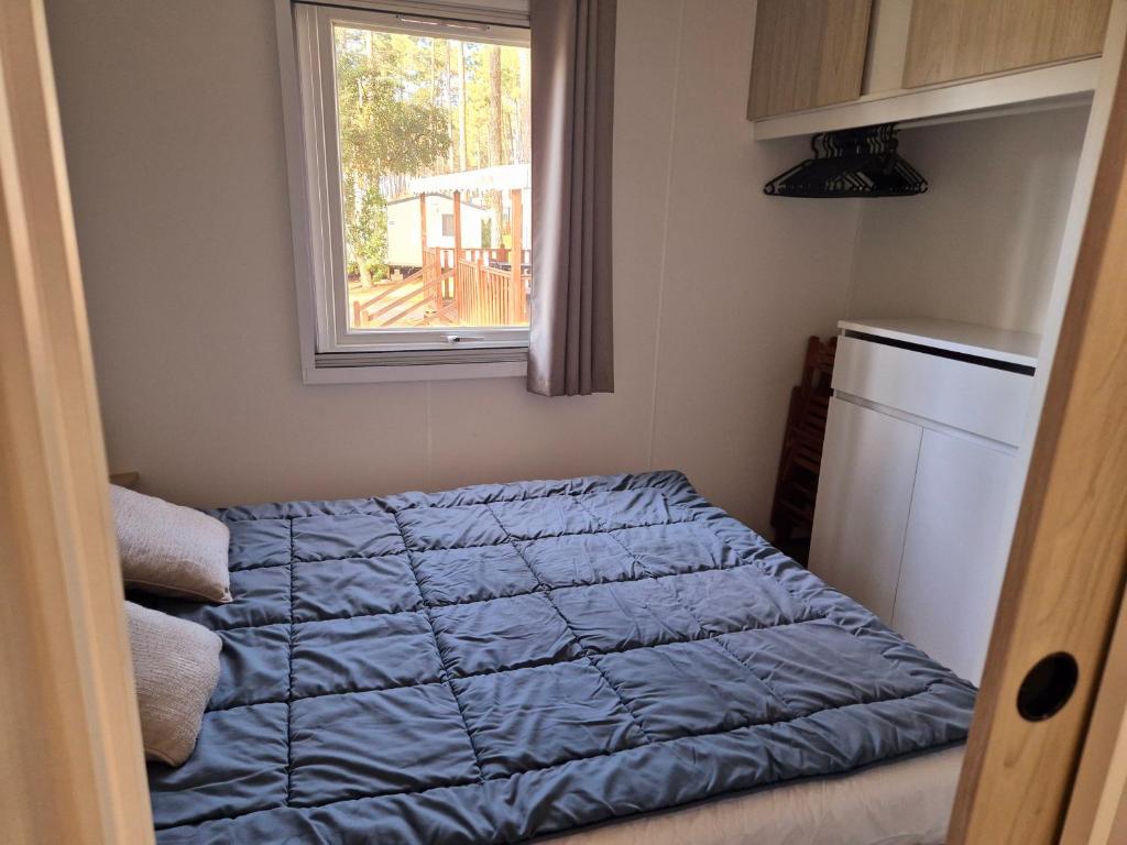 - une chambre avec une couette bleue et une fenêtre dans l'établissement MH 467 Isalisa 3chambres et 1 salle de bain dans camping 4 étoiles avec PARC AQUATIQUE, à Saint-Julien-en-Born