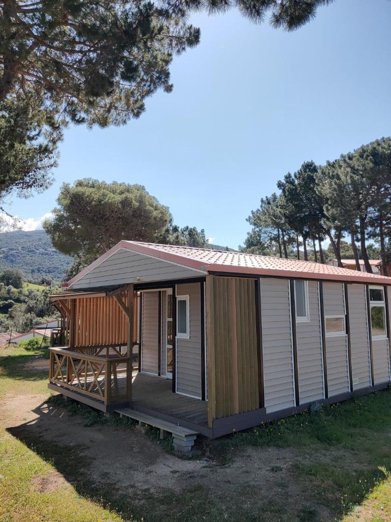 une petite maison avec un porche et une terrasse dans l'établissement Camping TIKITI, à Propriano