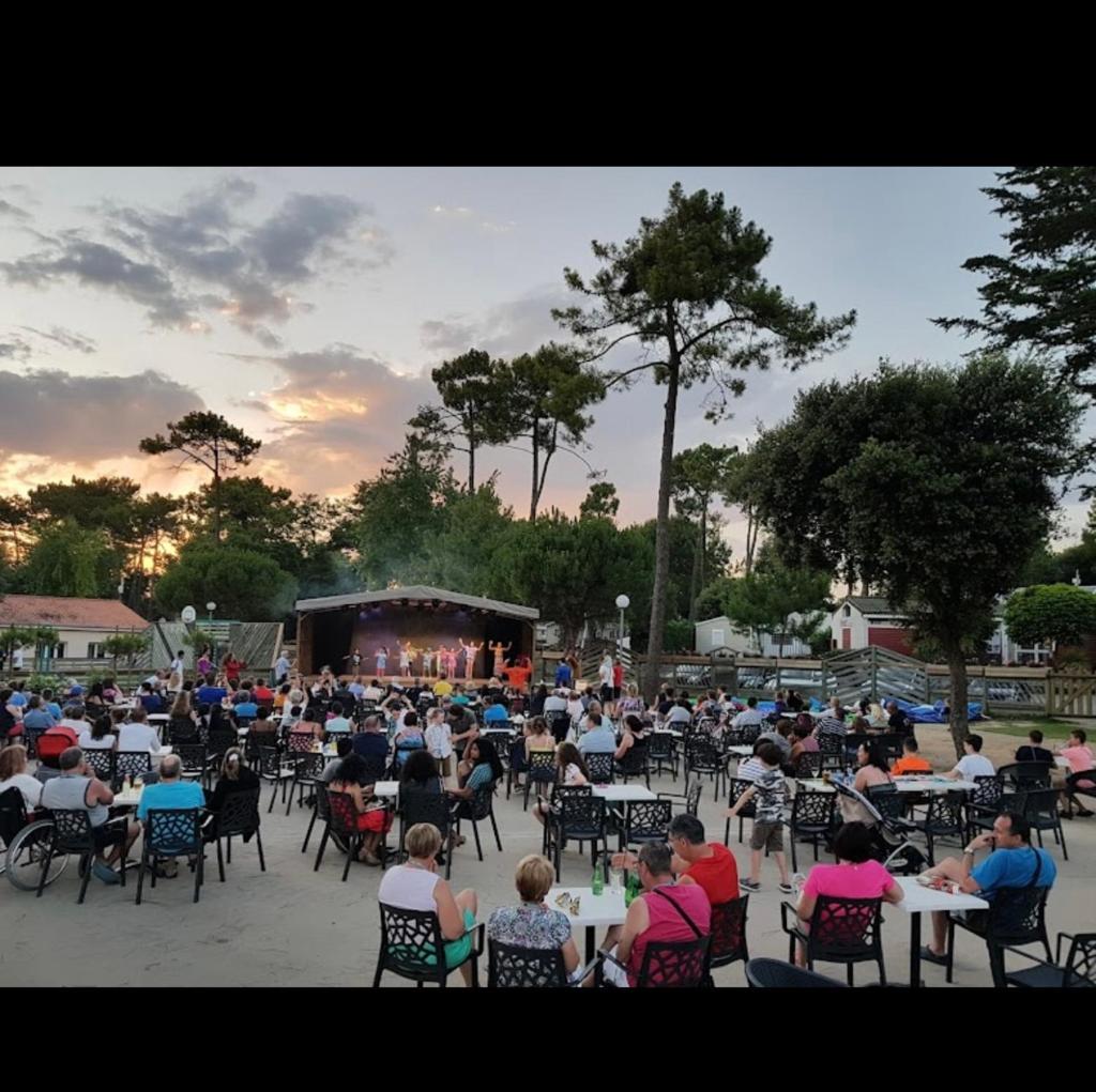 Une foule de personnes assises sur des chaises pour assister à un concert dans l'établissement MH 148, camping bois dormant, 2ch, 4 pers, à Saint-Jean-de-Monts 12 autres photos