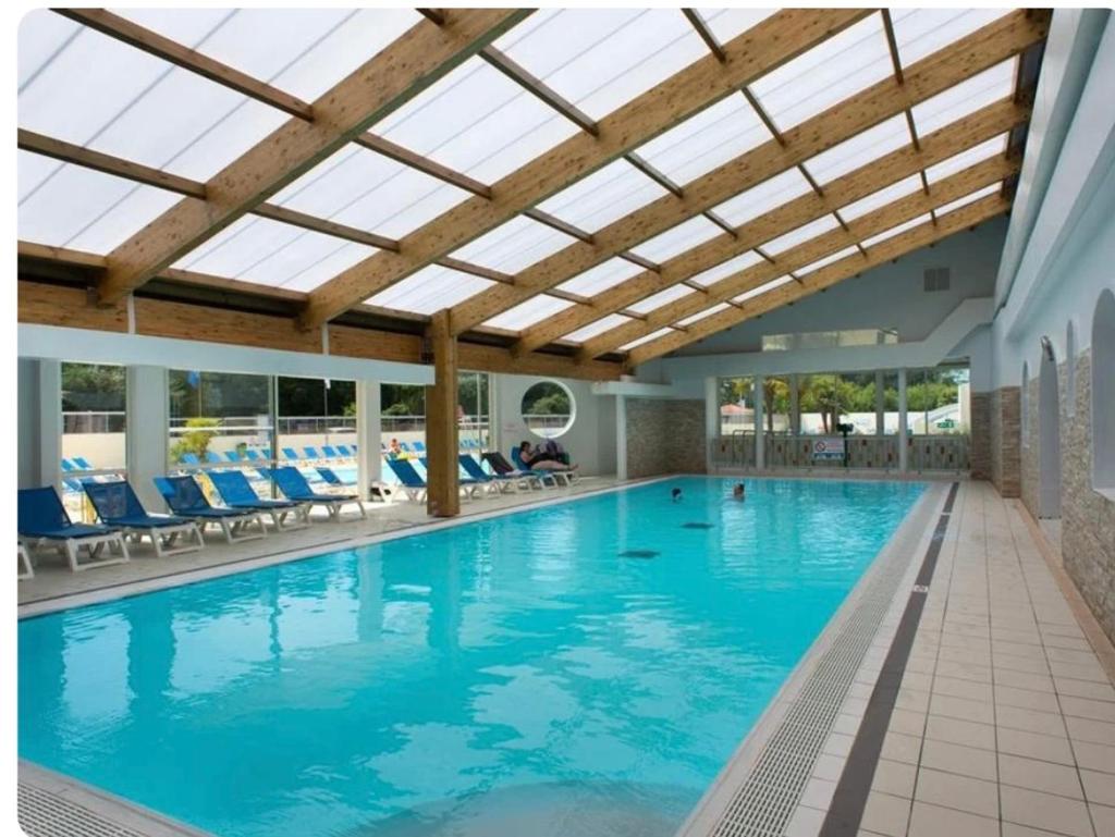 une grande piscine avec des chaises bleues et un plafond dans l'établissement MH 148, camping bois dormant, 2ch, 4 pers, à Saint-Jean-de-Monts
