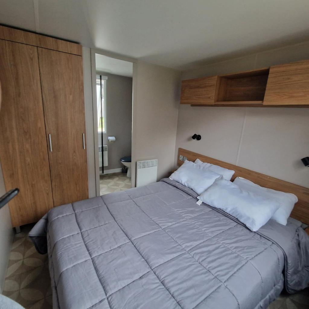 - une chambre avec un grand lit et des placards en bois dans l'établissement Camping de Bayadene, à Piriac-sur-Mer