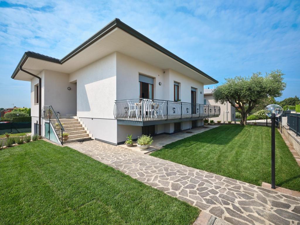 Cette maison blanche dispose d'un balcon et d'une pelouse. dans l'établissement VILLA HARMONY - Regarda Travel, à Lazise
