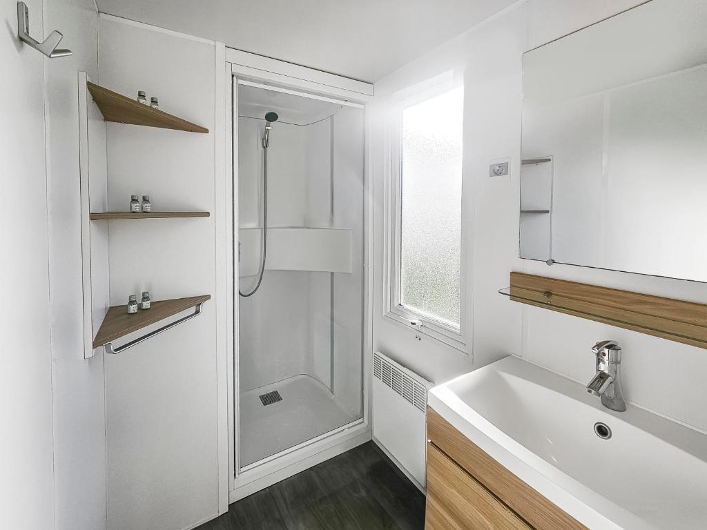 une salle de bain blanche avec une douche et un lavabo dans l'établissement Mobile Home Luca - Séjour Nature, à Litteau