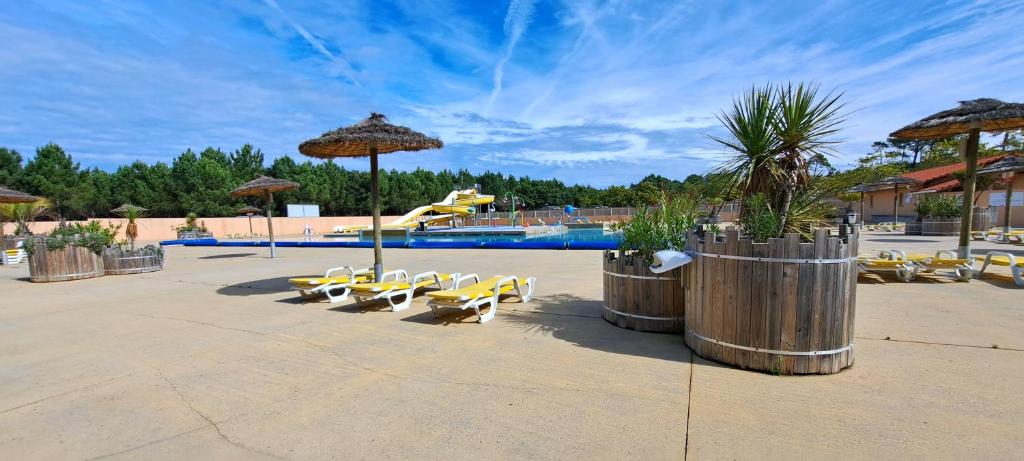- une piscine avec des chaises et des parasols jaunes dans un complexe dans l'établissement Mobil Home Camping 4 étoiles les Oyats, à Seignosse