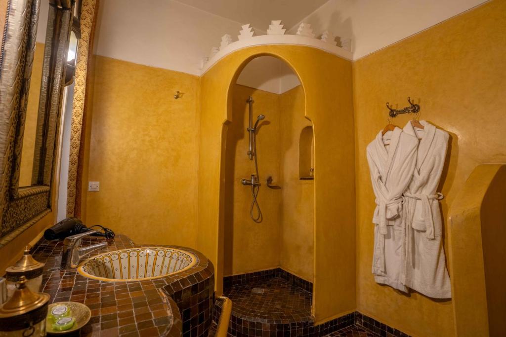 La salle de bains est pourvue d'une douche et d'un peignoir accroché au mur. dans l'établissement Riad Alaka, à Marrakech