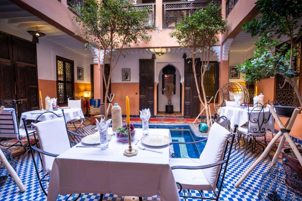 une salle à manger avec des tables et des chaises blanches et une piscine dans l'établissement Riad Alaka, à Marrakech