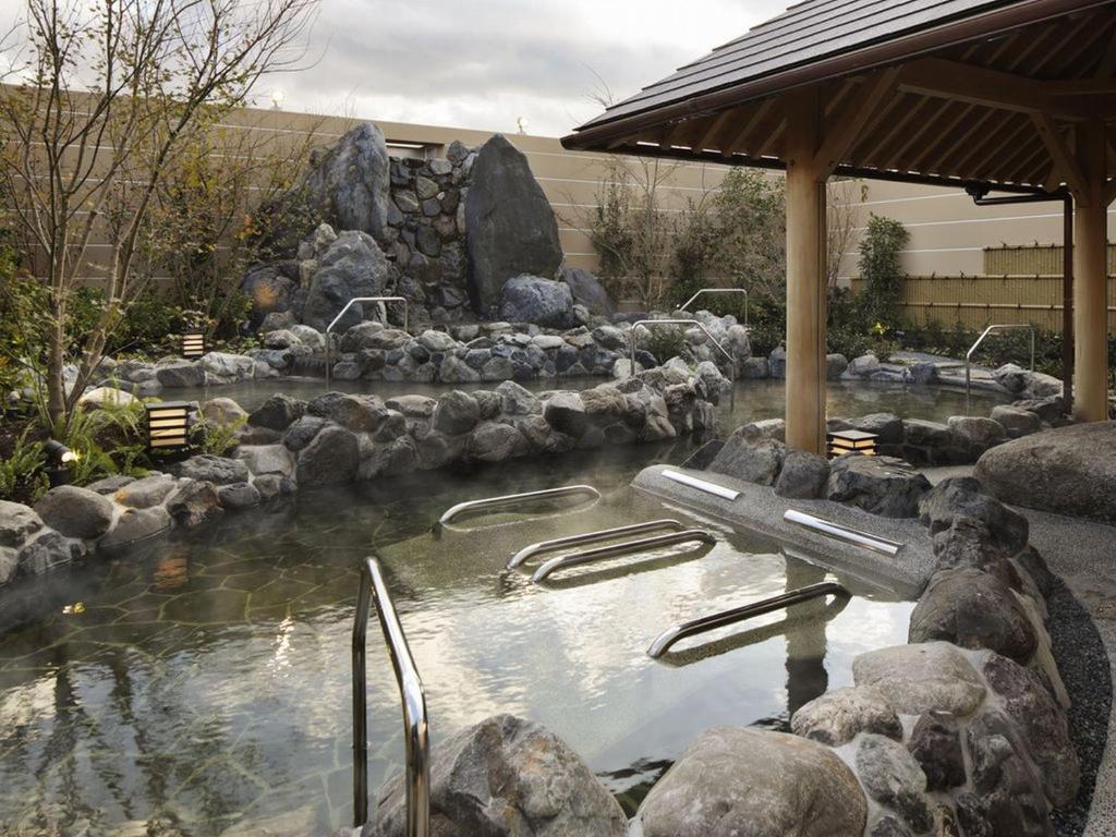 une piscine d'eau avec des rochers dans un jardin dans l'établissement Kobe Minato Onsen Ren, à Kobe