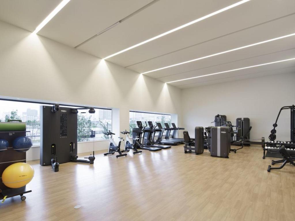 une salle de sport avec des rames de tapis roulants et des machines dans l'établissement Kobe Minato Onsen Ren, à Kobe