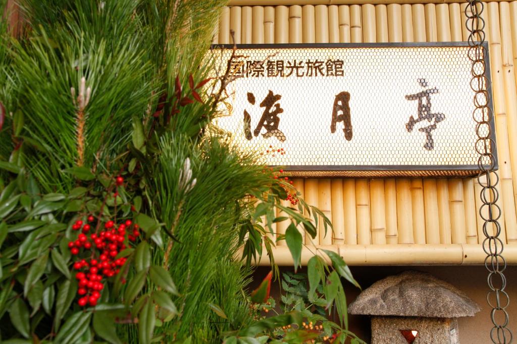 un panneau suspendu sur un mur avec un arbre de Noël dans l'établissement Kyoto Arashiyama Onsen Ryokan Togetsutei, à Kyoto