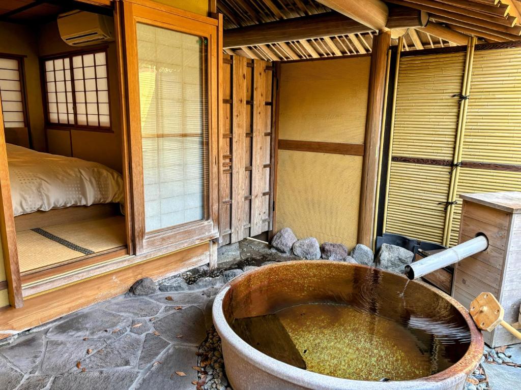 - une baignoire dans une chambre avec un lit dans l'établissement Yufuin Santoukan, à Yufu