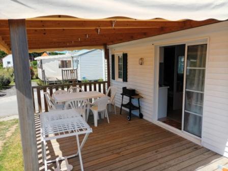 - une terrasse couverte avec une table, des chaises et un parasol dans l'établissement Mobil home LA BAULE 437, à La Baule
