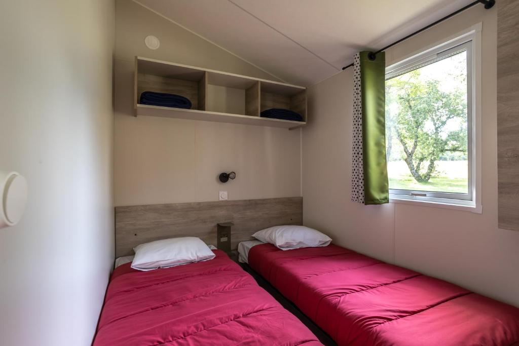 - deux lits dans l'angle d'une chambre avec des draps rouges dans l'établissement Camping le Petit Liou Sites & Paysages, à Baratier
