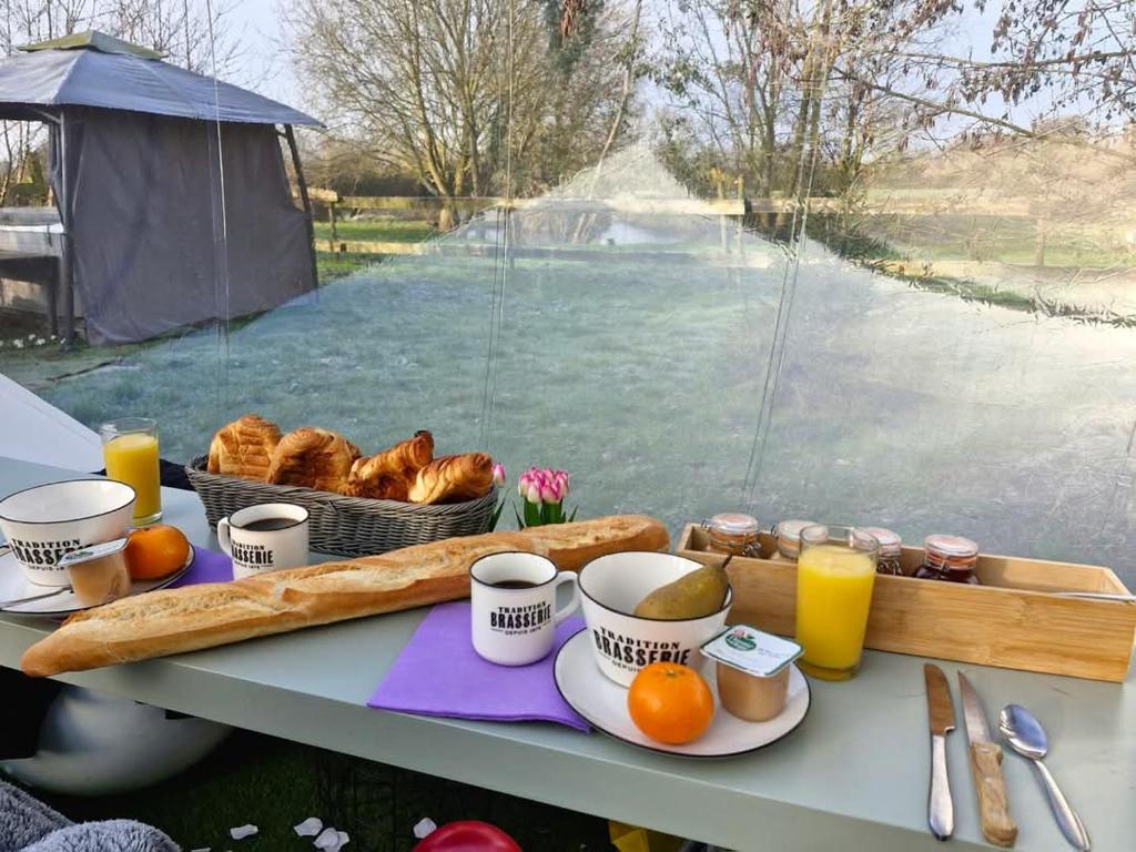 - une table avec un plateau de pain et du jus d'orange dans l'établissement La bulle, à Attiches