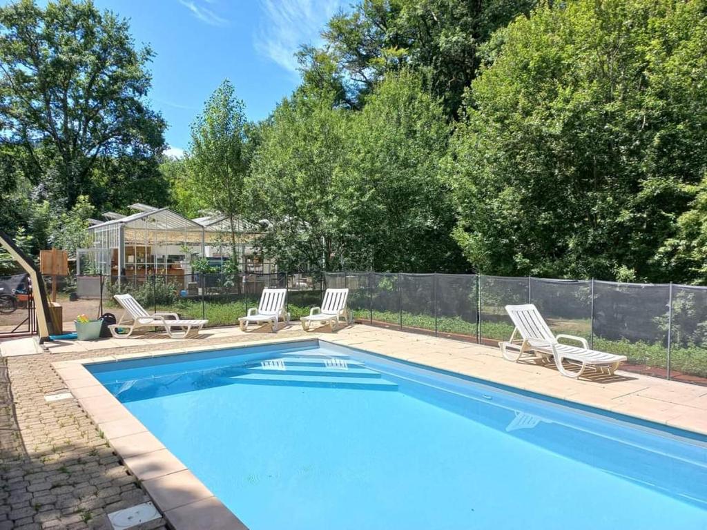 une piscine avec deux chaises longues et une clôture dans l'établissement Camping Terre Rouge, à Villecomtal