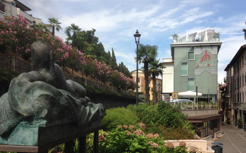 une statue d'une personne allongée sur un banc dans l'établissement Happy Hotel Atelier Gardone Riviera Centro & Spa, à Gardone Riviera