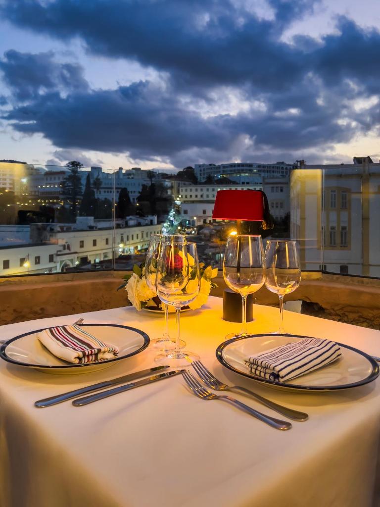 une table avec des verres à vin et une vue sur une ville dans l'établissement RIAD TANJA by chef Moha, à Tanger
