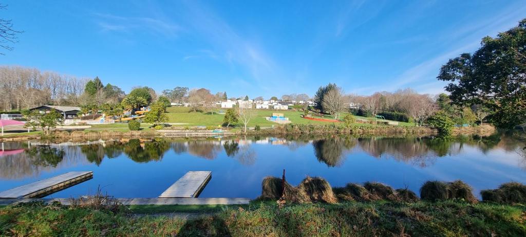 un lac dans un parc avec deux bancs dans l'établissement Camping Paradis Domaine de Bel Air, à Landudec 9 autres photos