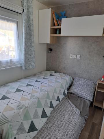une petite chambre avec un lit et une fenêtre dans l'établissement Le Cozy'Land - Mobilhome Camping La Réserve, à Gastes 20 autres photos