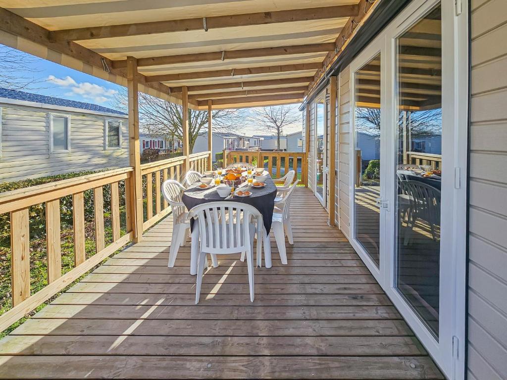 une terrasse en bois avec une table et des chaises dessus dans l'établissement L'orchidée des bois, à Litteau