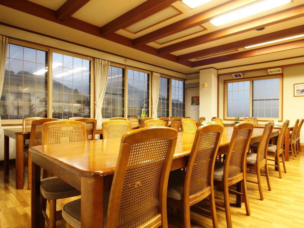 une salle à manger avec tables, chaises et fenêtres dans l'établissement Hatoguruma Kawabata, à Nozawa Onsen
