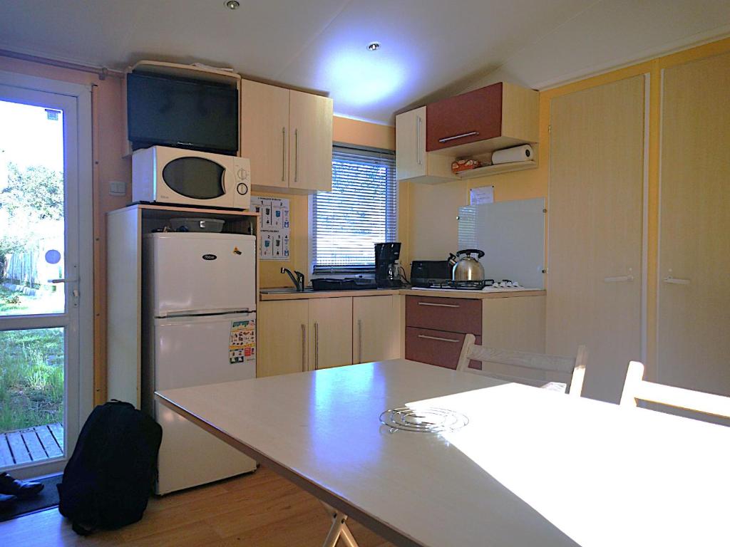 une cuisine avec un réfrigérateur blanc et une table dans l'établissement PuyduFou MH F4 FULL CONFORT 6personnes 220FS, à La Boissière-de-Montaigu