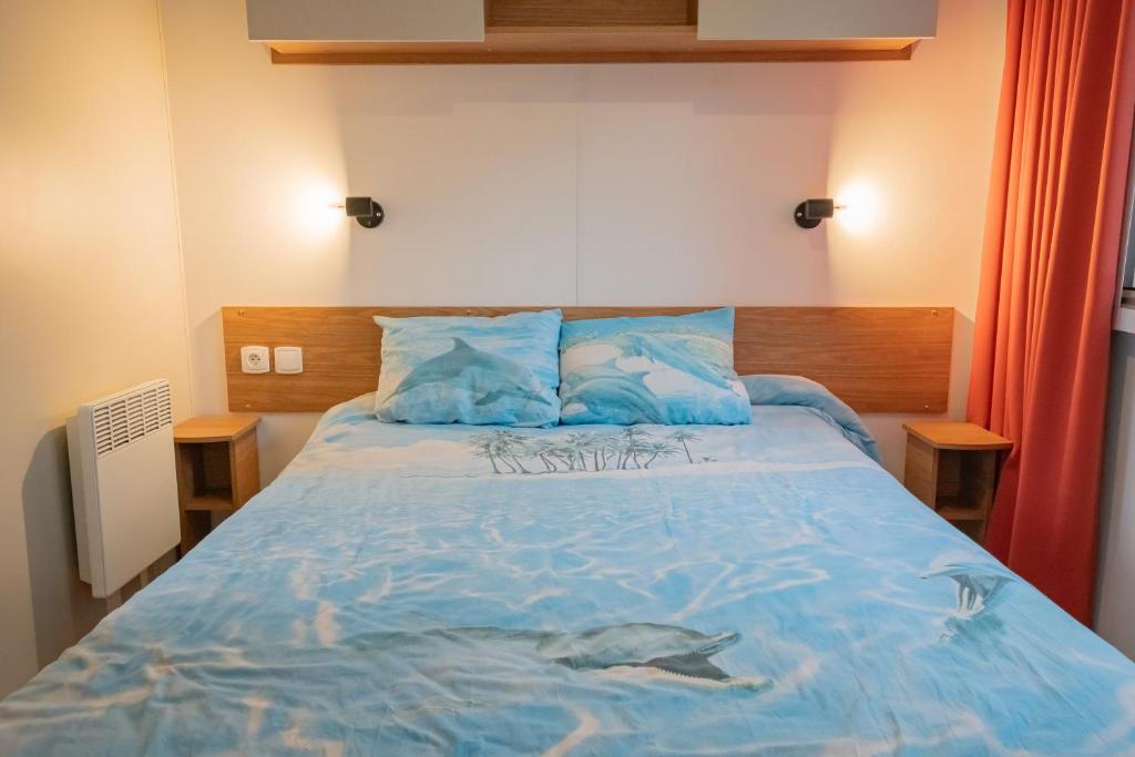 une chambre avec un grand lit avec des draps bleus dans l'établissement La Cabane du Bassin, à Lège-Cap-Ferret
