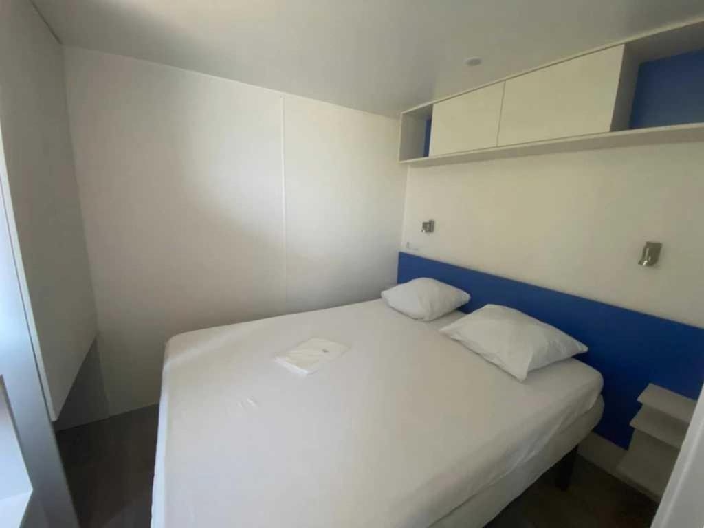 un lit blanc avec deux oreillers dans une petite pièce dans l'établissement Camping 2 étoiles - Piscine - ccb0feg, à Villeneuve-lès-Maguelone