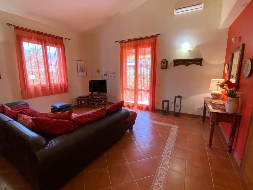 - un salon avec un canapé noir et des rideaux rouges dans l'établissement Le Case di Palma - Villa Maria, à Custonaci