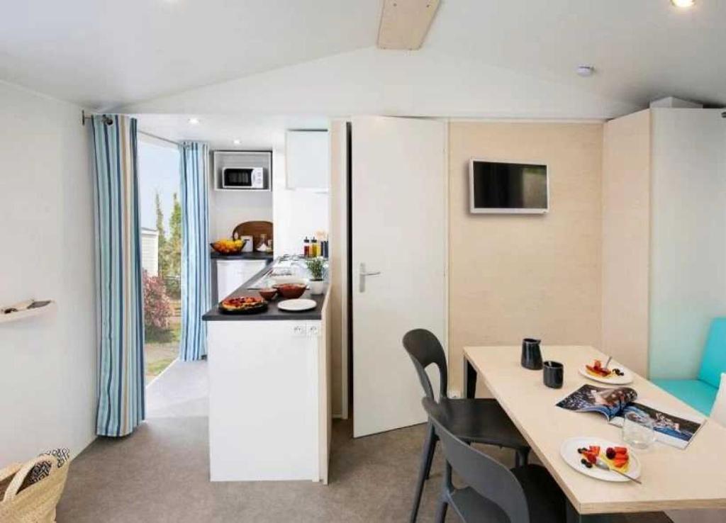 une cuisine et une salle à manger avec une table et des chaises dans l'établissement Camping - Parc aquatique - ccaggcd, à Olonne-sur-Mer