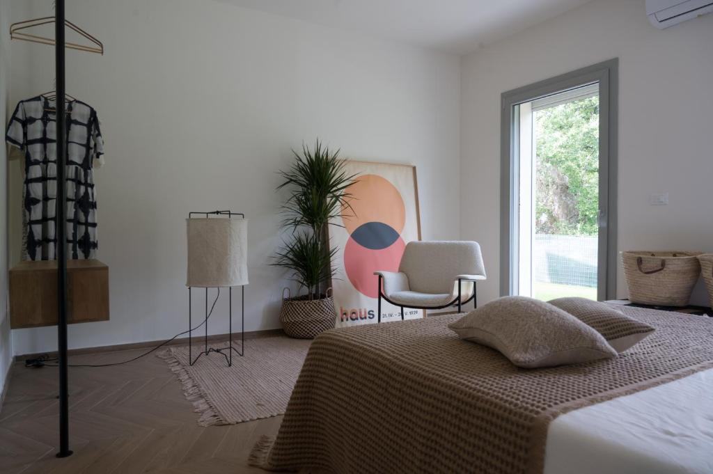 une chambre avec un lit, une chaise et une fenêtre dans l'établissement Villa La Leccina a Castellina Marittima, à Castellina Marittima