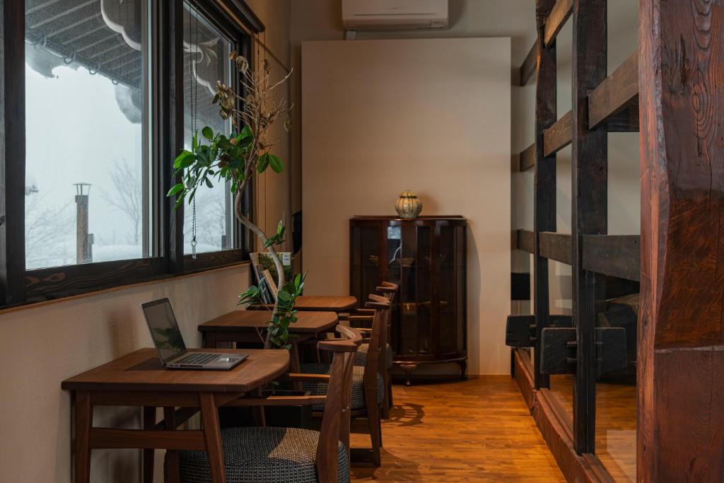 un restaurant avec des tables et des chaises en bois et une fenêtre dans l'établissement Onsen and Garden Nana, à Kanazawa