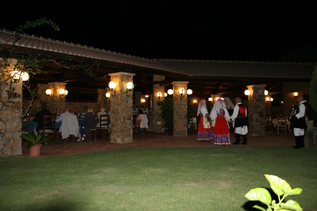 un groupe de personnes debout dans une cour la nuit dans l'établissement Hotel Spartivento, à Chia