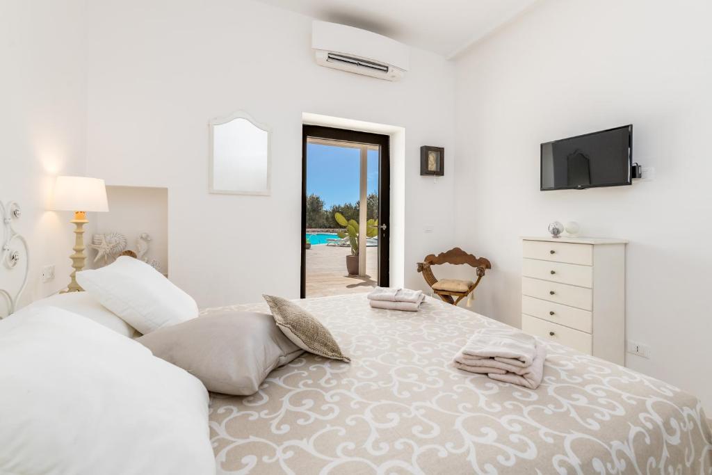 une chambre blanche avec un grand lit et une télévision dans l'établissement LA CORTE BIANCA LUXURY VILLA, à Ostuni