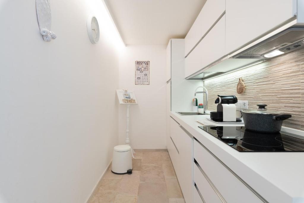 une cuisine avec des armoires blanches et un four à plaques de cuisson dans l'établissement LA CORTE BIANCA LUXURY VILLA, à Ostuni