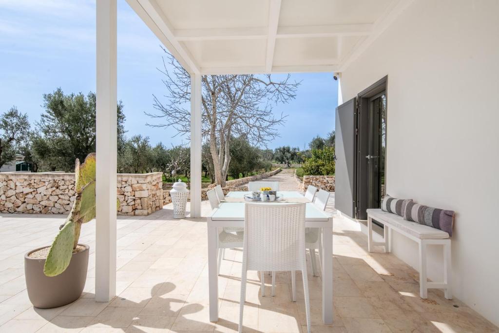 - un patio blanc avec une table et des chaises blanches dans l'établissement LA CORTE BIANCA LUXURY VILLA, à Ostuni