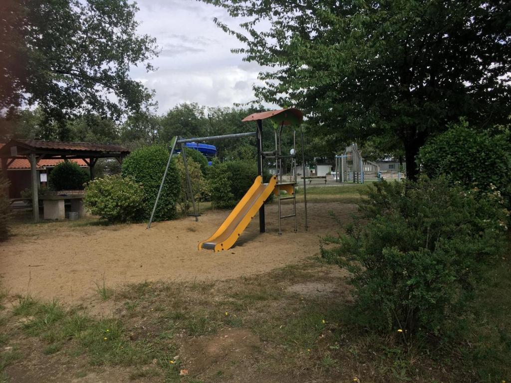 une aire de jeux avec toboggan jaune dans un parc dans l'établissement Mobilhome 5P proche Puy duFou 120CV, à La Boissière-de-Montaigu