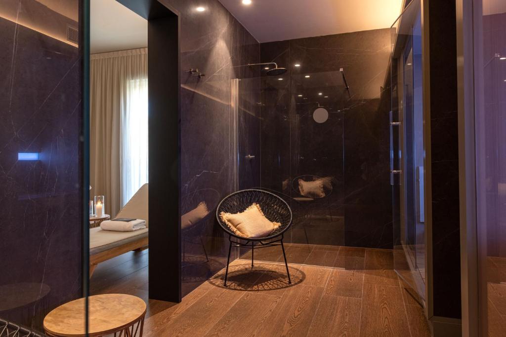 La salle de bains est pourvue d'une douche en verre et d'une chaise. dans l'établissement Villa Regina - MarePineta Resort, à Milano Marittima