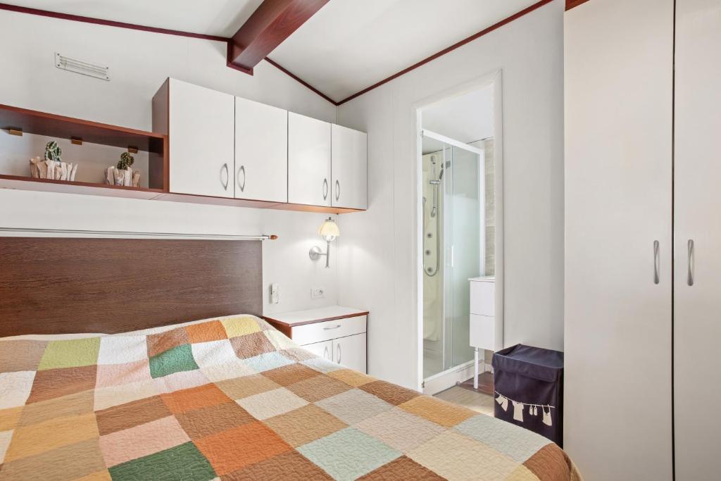 - une chambre avec un lit et des armoires blanches dans l'établissement Mobilhome Puget-sur-argens, à Puget-sur Argens